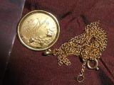 une pièce d'or entourée d'une chaîne, posée sur un tissu rouge