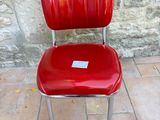 a red chair with a tag on it sitting in front of a stone wall