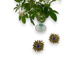 a vase with flowers in it and a pair of brooches on the table