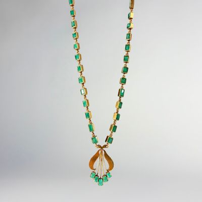 un collier composé de perles vertes et dorées et d'un pendentif en forme de feuille