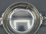 an antique silverplated bowl with handles on a black surface