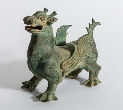 une vieille figurine en bronze représentant un dragon sur fond blanc