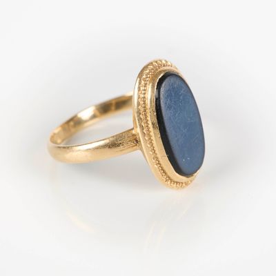 gros plan d'une bague en or avec une pierre bleue