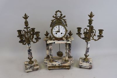 trois bougies et une horloge posées sur une table