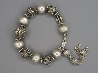 bracelet en argent orné de perles et d'une breloque en forme de couronne sur fond gris