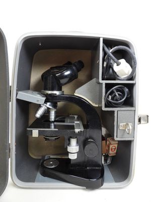 an open box with a microscope and other items in it
