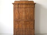 une vieille commode en bois adossée à un mur blanc