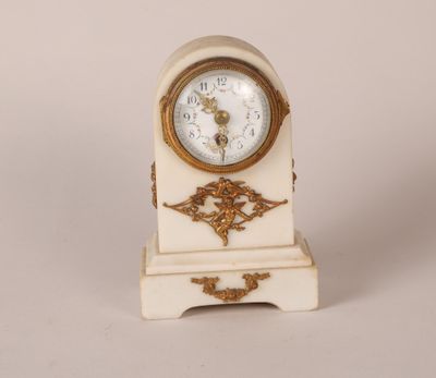 une petite horloge blanche et dorée posée sur une table