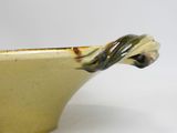 a yellow bowl with a handle on a white table