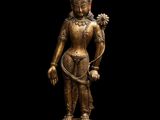 une statue en or représentant une femme tenant une fleur, posée sur un socle