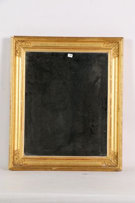 un miroir ancien à cadre doré accroché à un mur blanc, sur fond noir