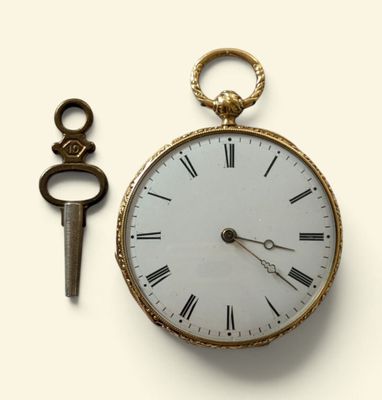une montre de poche en or et une clé posées sur une surface blanche