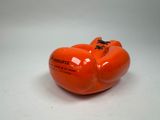 une pomme orange en forme de citrouille posée sur une surface blanche