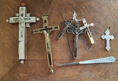 trois croix et un couteau posés sur une table en bois