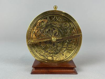 a close up of a brass clock on a wooden stand