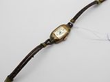 une photo d'une montre-bracelet posée sur une surface blanche, à laquelle est accrochée une étiquette