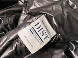 a label on a shiny jacket that is laying on a bed
