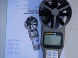 a digital thermometer sitting on top of a piece of paper next to a fan