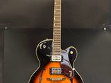 une guitare électrique orange et noire posée sur un support