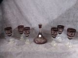 six wine glasses and a decanter sitting on a table