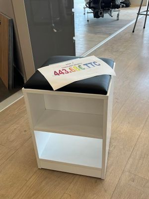 un tabouret noir et blanc sur lequel est posée une pancarte