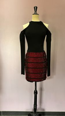 une robe posée sur un présentoir à mannequin, composée d'un haut noir et d'une jupe rouge