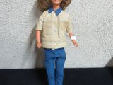 a doll with blonde hair and blue pants standing on a black surface