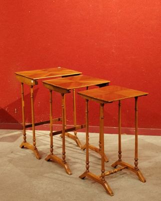 trois tables en bois posées sur un sol en béton, près d'un mur rouge