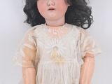 an old fashioned doll with black hair and a white dress