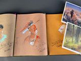 three books with drawings of native people and animals on them