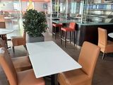tables and chairs in a restaurant with a bar in the background