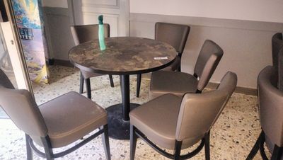 a table and chairs in a room with a painting on the wall