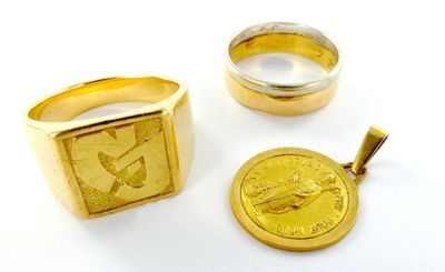 deux bagues en or et une pièce d'or sur un fond blanc