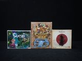 three video games are sitting on a black surface with a black background