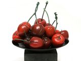 a bowl of cherries sitting on a black plate