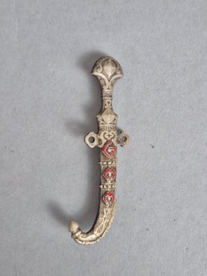 un vieux poignard en argent orné d'un motif rouge et blanc