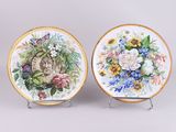 deux assiettes ornées de fleurs et d'un chat, posées sur un présentoir