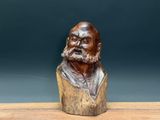 an old wooden bust of a man with a beard on a wooden table