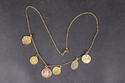 a close up of a necklace with coins on a black surface
