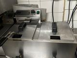 stainless steel counter top with two deep fryers and a counter top oven
