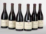 six bouteilles de vin sont alignées sur une table