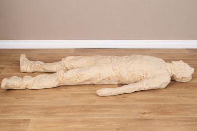 une statue en bois représentant un homme allongé sur le sol
