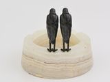 two black birds sitting on top of a wooden plate
