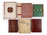 several old books are lined up on a white surface