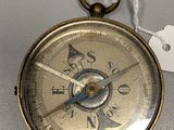 a small gold compass with a tag on it