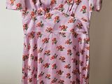 a pink floral dress hanging on a hanger in a room
