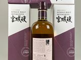 an empty bottle of whisky sitting next to a purple box