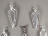 four clear glass bottles and a silver spoon on a white surface