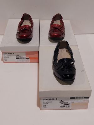 une paire de chaussures rouges et noires posée sur une boîte blanche