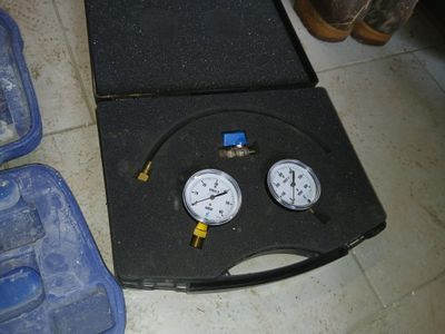 deux manomètres dans un étui posé par terre à côté d'une paire de chaussures